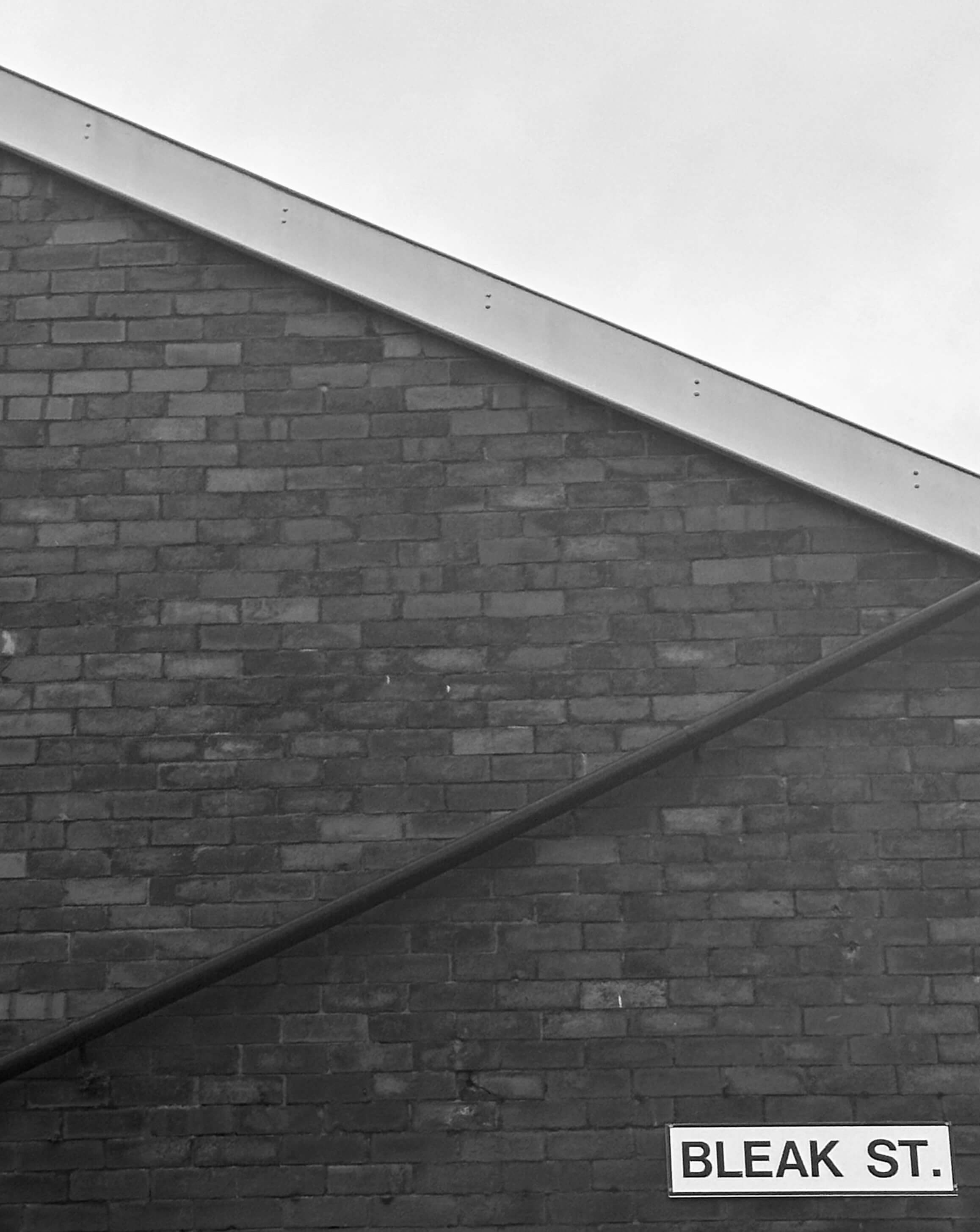 The side of a british house, the street sign reads 'Bleak Street'