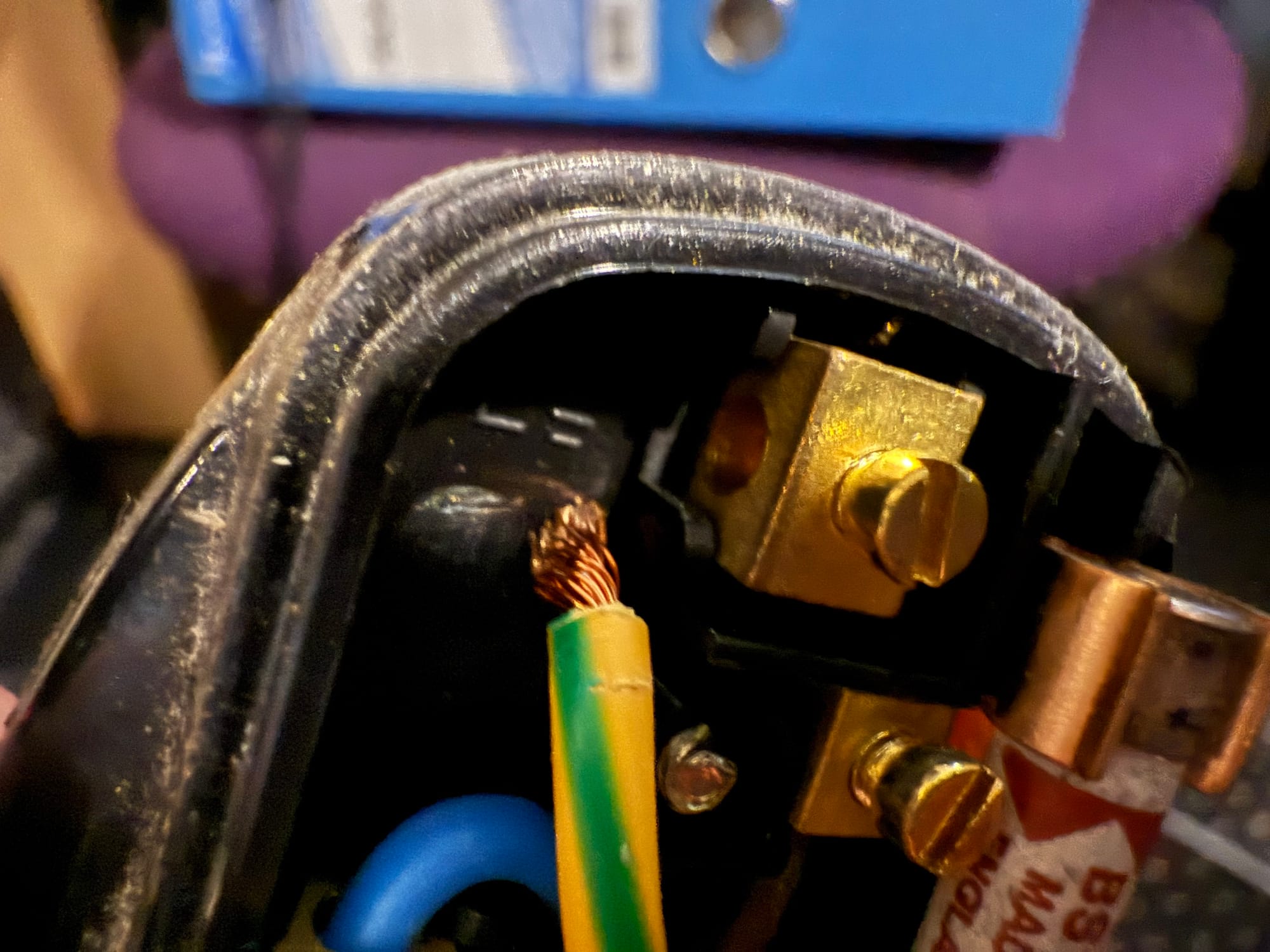 The inside of a UK plug socket, showing the earth wire is completely disconnected from the terminal.