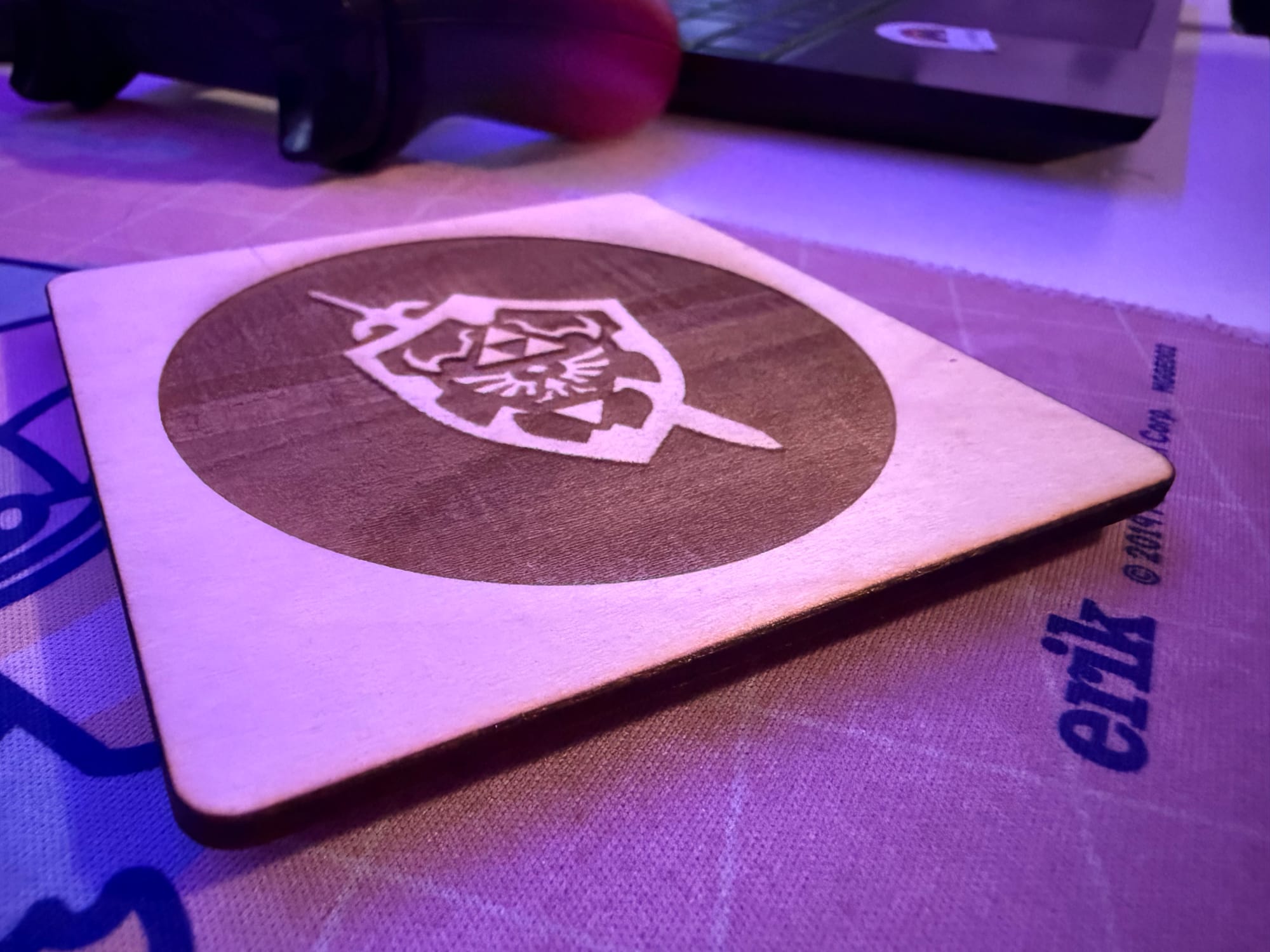 A wooden coaster with a zelda triforce engraved into it