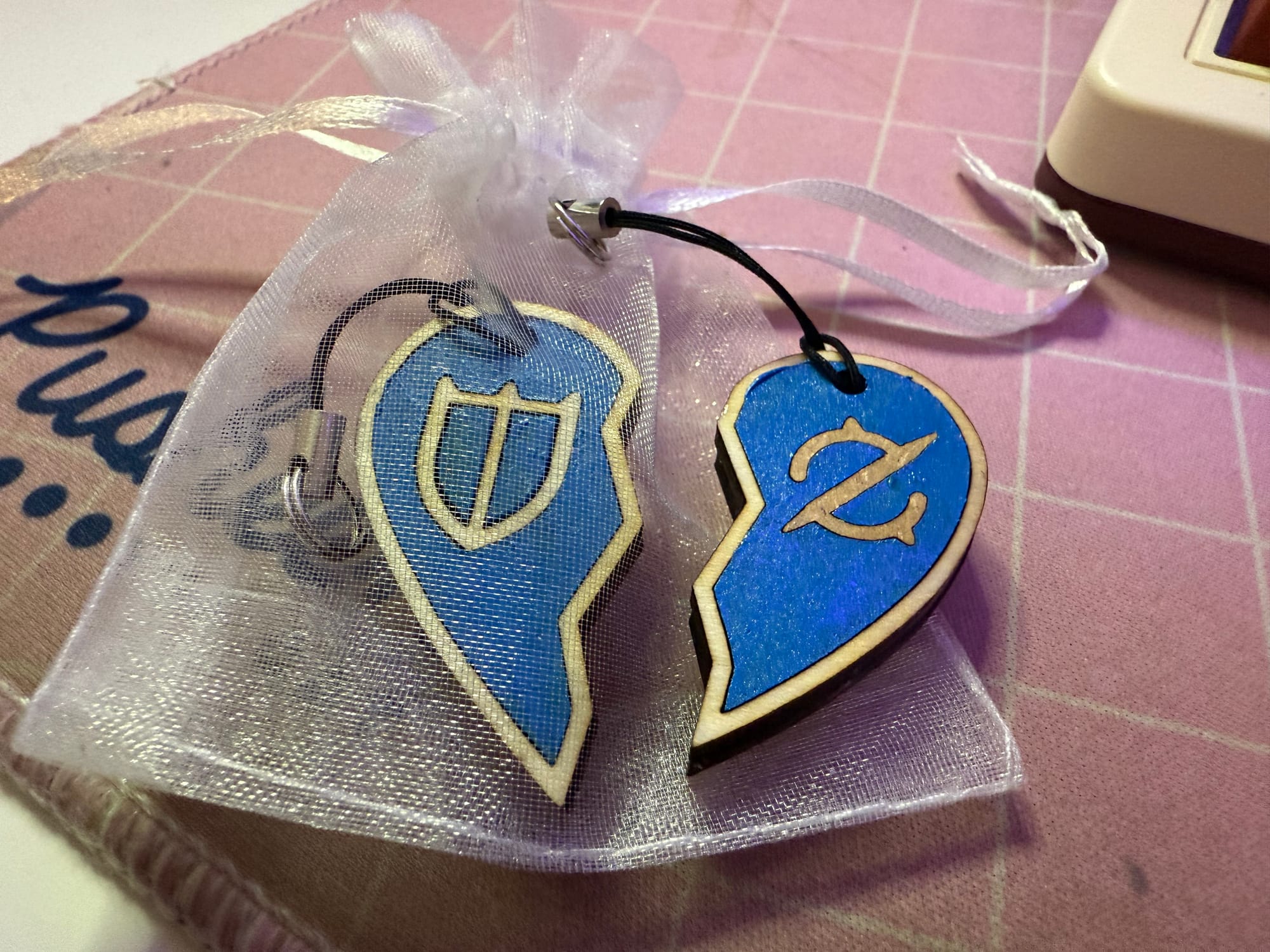 A keychain pair, each half is a broken heart, together making the whole. The designs for the Final Fantasy 14 jobs are on them, for Paladin on the left and Gunbreaker on the right